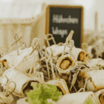 Vegetarische Wrap-Röllchen auf Salatbett mit Tafelschild als professionelles Fingerfood-Catering
