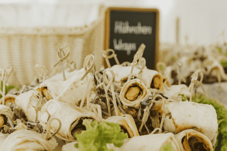 Vegetarische Wrap-Röllchen auf Salatbett mit Tafelschild als professionelles Fingerfood-Catering