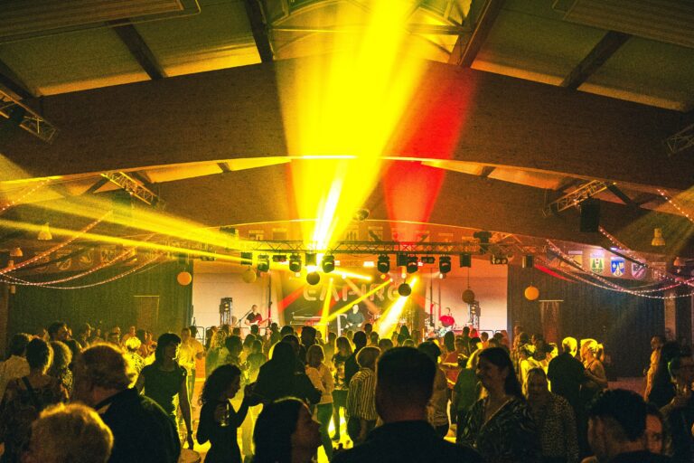Ü30-Party mit bunter Lichtshow und tanzender Menge in festlich geschmückter Eventhalle