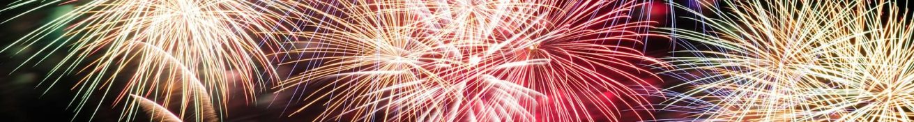 Buntes Feuerwerk mit goldenen, roten und blauen Lichteffekten am Nachthimmel, Silhouetten von Zuschauern im Vordergrund. Foto von Arthur Chauvineau auf Unsplash